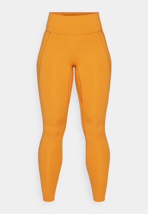 Pomarańczowe legginsy o wysokim stanie z gładkiej, elastycznej tkaniny, z detalami szwów wzdłuż boków dla dodatkowego efektu wizualnego.