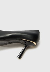 Pantof de damă cu toc înalt, de culoare neagră, realizat din piele netedă, cu un design elegant, având vârful ascuțit și un accent metalic aproape de toc.