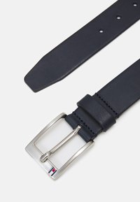 Marine lærbelte med sølvspenne, som har et lite aksent i rødt, hvitt og blått. Glatt tekstur med klassisk design og flere hull.