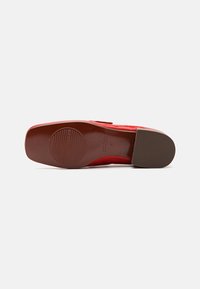 Sole de pantof din piele patent roșie, cu o formă rotunjită, având un design texturat pentru aderență și accente din cauciuc maro pe toc.
