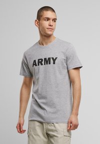 Pilkos medvilnės marškinėliai su žodžiu "ARMY" ryškiai juodomis raidėmis, apvaliu iškirpimu ir trumpomis rankovėmis. Lygi tekstūra, laisvas siluetas.