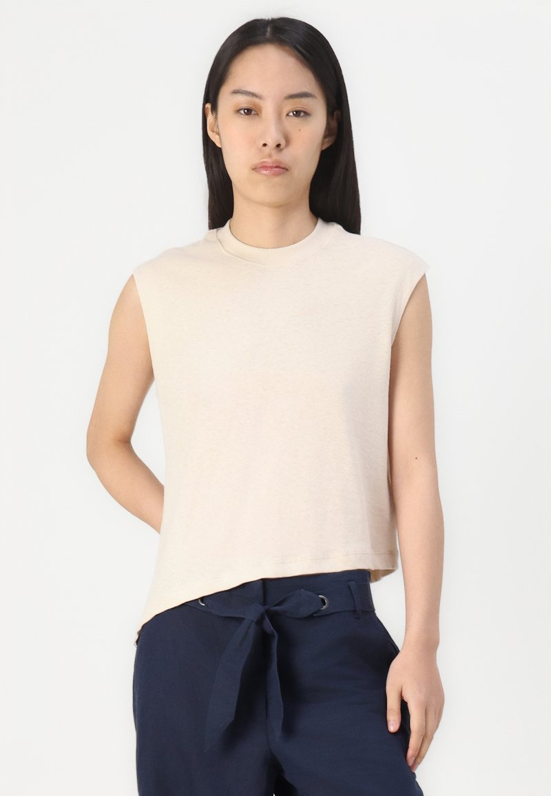 Beige ärmelloses T-Shirt aus weichem Stoff mit Rundhalsausschnitt und lockerer Passform. Gerader Saum mit leichtem Abfall hinten.