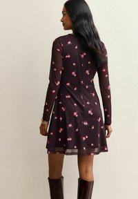 Abito bordeaux a maniche lunghe con un motivo floreale in rosa. Design svasato, maniche leggermente trasparenti e scollatura rotonda.