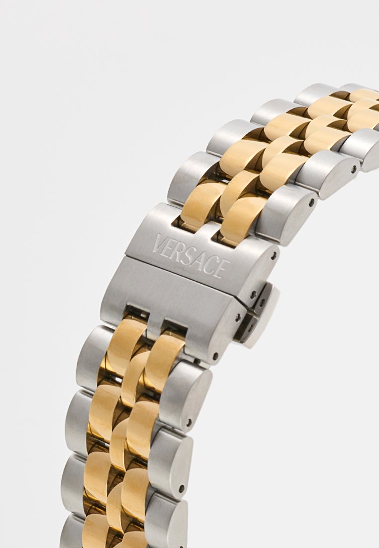 Montre Versace avec un bracelet en acier inoxydable argenté et en métal doré. Caractéristiques d'une finition polie et d'un logo gravé sur le fermoir.