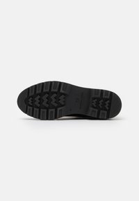 Black rubber shoe sole featuring a thick tread pattern with deep grooves and zigzag designs, marked with the size "37" and brand logo.