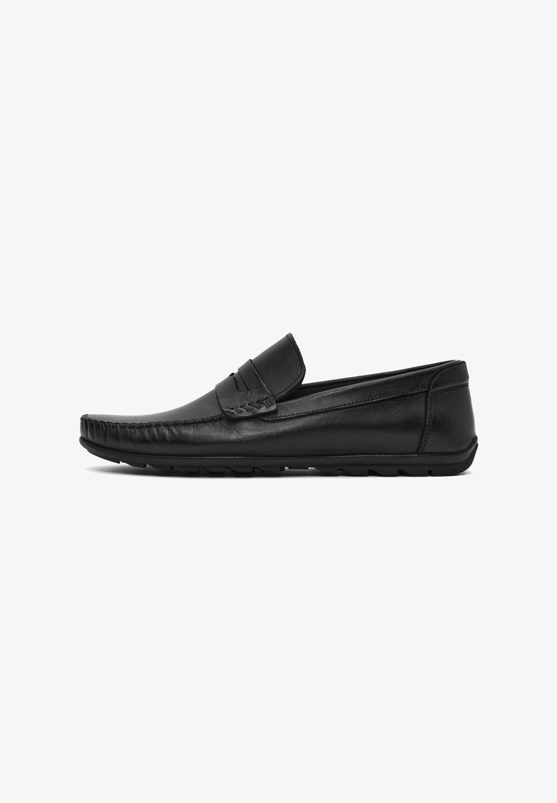 Mocasines de cuero negro con punta redondeada, acentos cosidos y una suela de goma de perfil bajo. Diseño tipo slip-on con una textura suave.
