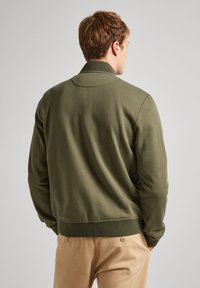 Sweatshirt vert olive avec un col et des poignets côtelés, texture lisse et silhouette ajustée. La vue de dos montre peu de détails.