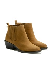 Bottines en suède sable à bout pointu, avec des panneaux latéraux élastiques et un talon carré. La texture est lisse avec une finition mate.