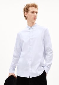 Lichtblauw katoenen overhemd met knopen, een klassieke kraag, lange mouwen en knopen aan de voorkant, met een subtiele embleem op de borst.