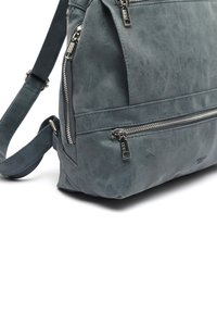 Grå faux läderväska med flera dragkedjefack, justerbar rem och en texturerad yta för extra detalj.