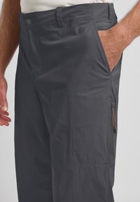 Donkergrijze lichtgewicht broek met een gladde textuur, zijzakken en een ritszak met een bronzen trekhaak.