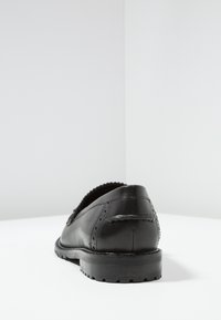 Zwarte leren schoen met een gladde afwerking, ronde neus, decoratieve stiksels en een gestructureerde rubberen zool. Minimalistisch ontwerp zonder zichtbare hardware.