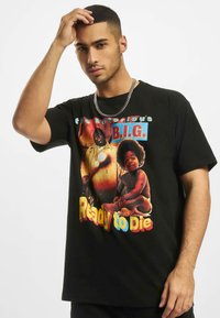 T-shirt en coton noir avec un design graphique coloré comprenant des figures et le texte "the Notorious B.I.G. Ready to Die." Manches courtes.