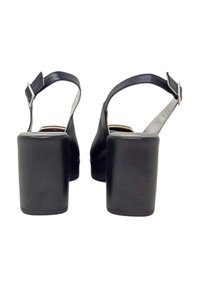 Tacchi slingback in pelle nera con tacco quadrato, texture liscia e chiusura a fibbia alla caviglia.