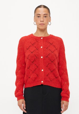 Rode gebreide cardigan met een ruitvormig kantpatroon, ronde halslijn en vijf witte knopen aan de voorkant. Lange mouwen met ribgebreide manchetten.