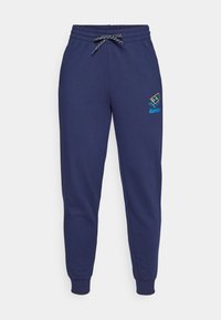 Mørkeblå joggebukser med snøring i livet og ankelsømmer. Har en Lotto-logo i livlige farger på venstre lår. Laget av myk stoff.