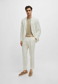 Abito a scacchi chiaro, design attillato, tessuto strutturato, abbinato a un top beige, cintura marrone chiaro e mocassini marroni con nappe.