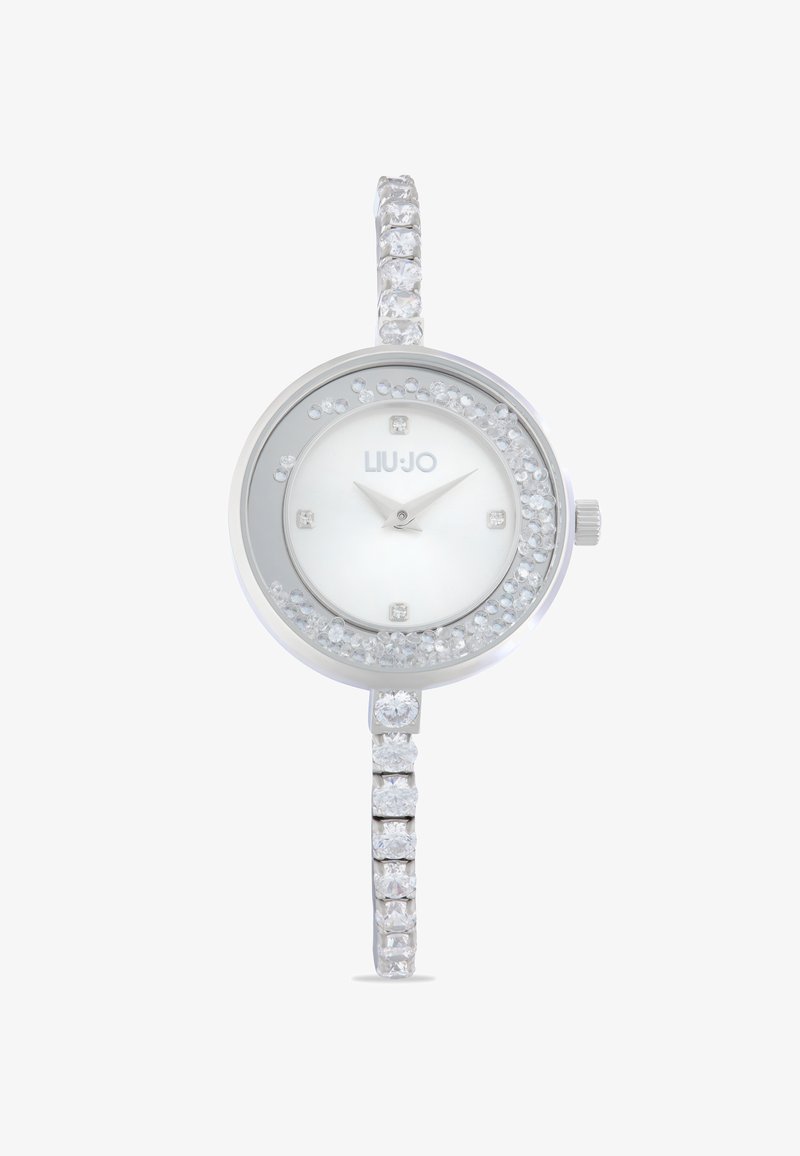 Silberne Uhr mit rundem Ziffernblatt, weißem Ziffernblatt, Kristallakzenten und einem funkelnden Armband, das mit abwechselnd quadratischen und runden Steinen verziert ist.