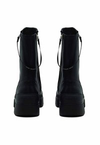 Zwarte leren enkelboots met een gladde afwerking, ritsen en trekbandjes aan de achterkant, met dikke plateauzolen.