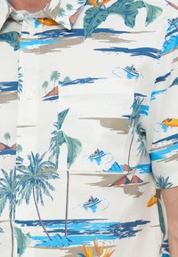 Λευκό πουκάμισο με κουμπιά, σε τροπικό σχέδιο που απεικονίζει φοίνικες, νησιά, κύματα ωκεανού και ανθρώπους που κάνουν τζετ σκι.