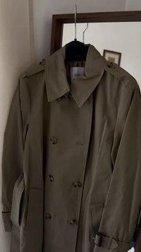 Doppelreihiger Trenchcoat in olivgrün. Mit großem Kragen, strukturiertem Stoff, zwei Seiten taschen und einem Gürtel mit Schnallen-Detail.