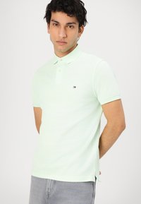 Lysegrøn bomulds polo t-shirt med korte ærmer, krave, to knapper og et lille logo på venstre bryst. Sideslids i kanten.
