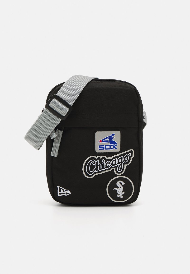 Schwarze Stoff-Schultertasche mit einem grauen verstellbaren Tragegurt. Auf der Vorderseite befinden sich Logos und Abzeichen der Chicago White Sox. Quadratische Form, mit Reißverschluss.