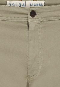 Khaki cotton pants with a zip fly, button closure, and front pockets. Features a smooth texture and straight cut. Size label visible.