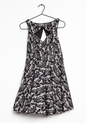 Schwarzes Spitzenkleid mit Blumendruck, ausgestattet mit einem Schlüsselloch-Ausschnitt, einem plissierten Rock und einem runden Ausschnitt, hängt von einem schwarzen Kleiderbügel.