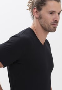 Zwarte T-shirt met korte mouwen en V-hals, gemaakt van een gladde stof, met een aansluitend ontwerp, subtiele naden en een strakke silhouette.