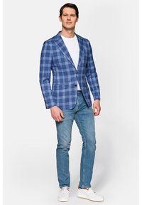 Niebieska marynarka w kratę z klapami, na pojedynczy guzik, z przednimi kieszeniami; zestawiona z białym t-shirtem i jasnoniebieskimi dżinsami, dopełniona sneakersami.