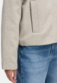 Hellgraue Wolljacke mit geradem Schnitt, ausgestattet mit einem strukturierten Stoff und einem vertikalen Nahtdetail am Ärmel; beinhaltet eine Tasche mit silberner Hardware.