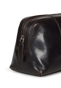 Pochette in pelle marrone scuro con finitura testurizzata, dotata di una cerniera metallica e di una linguetta laterale per una facile maneggevolezza. Forma quadrata con base piatta.