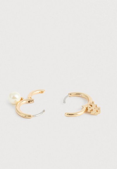 Χρυσά σκουλαρίκια κρίκοι με μία πέρλα και διακοσμητική μεταλλική λεπτομέρεια. Λείο υφάδι, κυκλικό σχήμα και ανοιχτός σχεδιασμός.