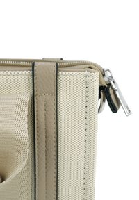 Close-up van de hoek van een beige canvas tas met leren riemdetail en zilveren ritsaantrekker op een witte achtergrond.