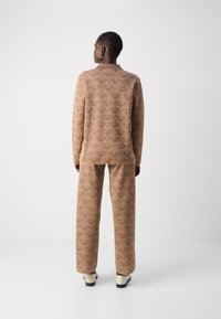 Braun gemusterter Oversize-Pullover und passende weit geschnittene Hose, mit einem geometrischen Design, aus weichem Stoff, mit lockerer Passform.