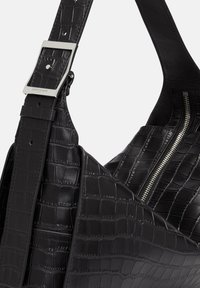 Sac à main en cuir noir avec une texture crocodile, featuring une boucle en argent sur la sangle et un compartiment zippé.