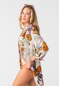 Květinové kimono s oranžovými, růžovými a zelenými motivy na krémovém pozadí; lehká, splývavá tkanina; rukávy po lokty; boční otvory.