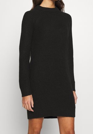 Robe en tricot noir avec une texture côtelée, un col rond, des manches longues et une coupe décontractée, avec un ourlet au-dessus du genou.