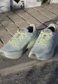 Light grey running shoes made of breathable material with green accents. Features include lacing system, texture on the upper, and GORE-TEX branding.