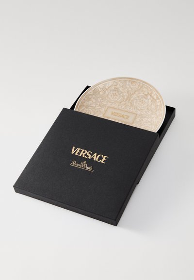 Dekoracyjny talerz Versace z kwiatowym wzorem w kolorze beżowym, w zestawie z czarnym pudełkiem z złotym napisem i akcentami logo.