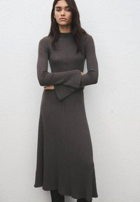 Vestido de manga larga con textura acanalada en color marrón oscuro. Presenta un top ajustado con mangas acampanadas y una falda fluida de corte en línea A.