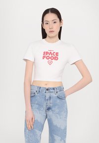 White cropped t-shirt featuring red "SPACE FOOD" graphic with heart logo; paired with light blue acid-wash jeans. Smooth cotton fabric.