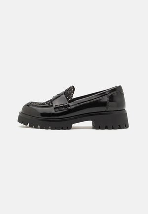 Mocassins en cuir verni noir avec un dessus en tissu texturé, une semelle en caoutchouc épaisse et des détails en bordure crantée distinctifs.