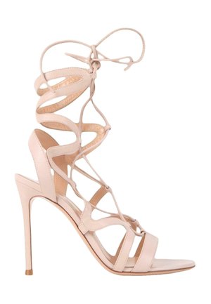 Sandale beige à talons hauts avec des lanières à lacets qui s'enroulent autour de la cheville et un design à bout ouvert sur fond blanc.