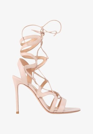 Sandale beige à talons hauts avec des lanières à lacets qui s'enroulent autour de la cheville et un design à bout ouvert sur fond blanc.