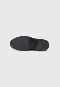 Semelle de chaussure noire avec une finition lisse et mate. Présente une légère courbure et un minimum de détails. Conçue pour l'adhérence et la stabilité.