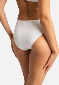 Sous-vêtements blancs côtelés taille haute présentant une couleur unie, des bords sans couture et une texture douce, montrés de profil.