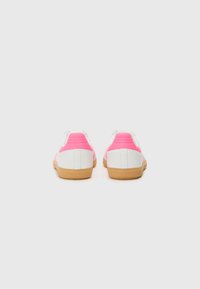 Zapatillas retro blancas y rosas con un talón texturizado rosa, suela de goma y parte superior blanca suave. Adecuadas para uso casual.