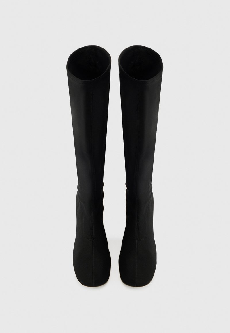 Knielange schwarze Stiefel aus glattem, elastischem Stoff, mit abgerundeter Spitze und schmalem Schnitt für eine enganliegende Silhouette. Keine sichtbaren Beschläge oder Muster.